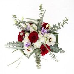 From the skilled hands of a Wembley florist, this arrangement radiates both distinction and unity. The rich spirals of deep red roses draw the eye first, hinting at enduring affection-a familiar sentiment on Wembley's eventful streets. They're anchored by white gerberas, their petals pure and creamy, fanned out around espresso-coloured centers for a timeless, composed look. Above the main blooms, flurries of silver-green eucalyptus leaves drift lightly, bringing airiness and a hint of fragrant coolness, much like the wafting breezes over Barham Park. Wisps of lilac lisianthus offer contemporary elegance, their gentle hues suggesting twilight over Brent Reservoir. Close inspection reveals clusters of delicate, fluffy white filler flowers that bring roundness, softness and a sense of abundance. Dark green, broad leaves tightly wrap the base like a ribbon, holding the bouquet in a poised, refined form within a clear vase-every green stem and bubble of water visible for all to see. This arrangement fits seamlessly into Wembley's diverse homes, whether for commemorating a special event, expressing gratitude, or lifting the mood in daily spaces with its modern composition and vibrant freshness.